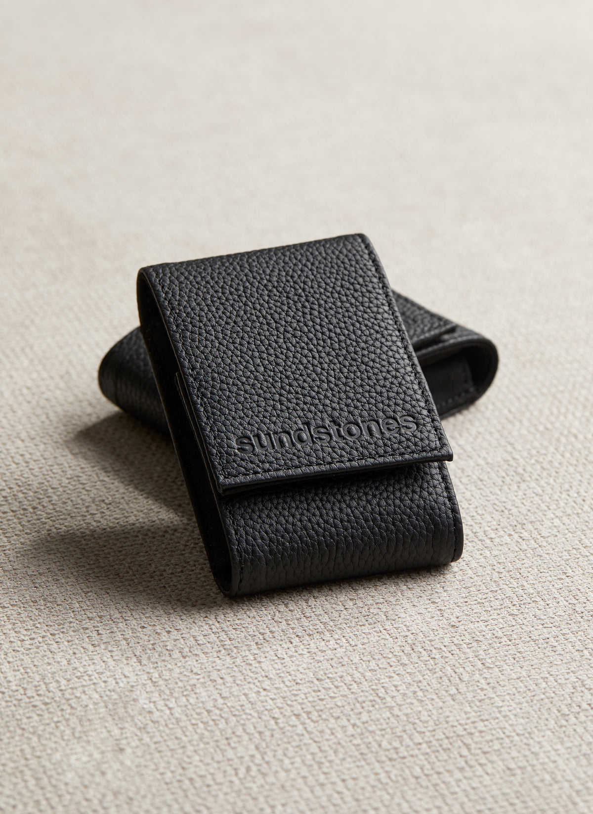 
Arcus Onyx black leather watch pouch with embossed logo on a fabric surface